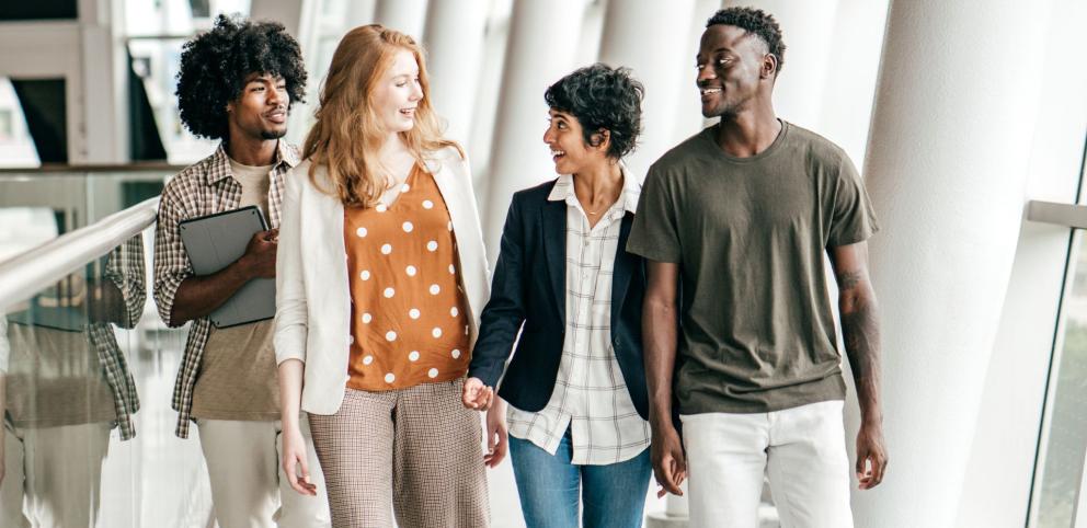 Image of four students walking down a campus hallway